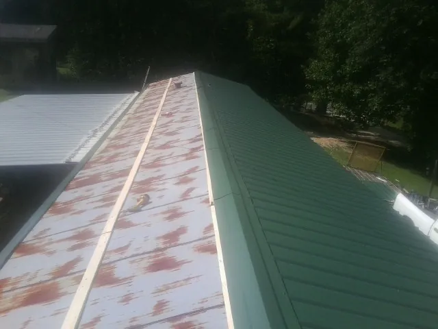 Old rusted panels beside newly installed green metal roofing — Wind Damage Roof Repair by Roofing Brothers in Keyport