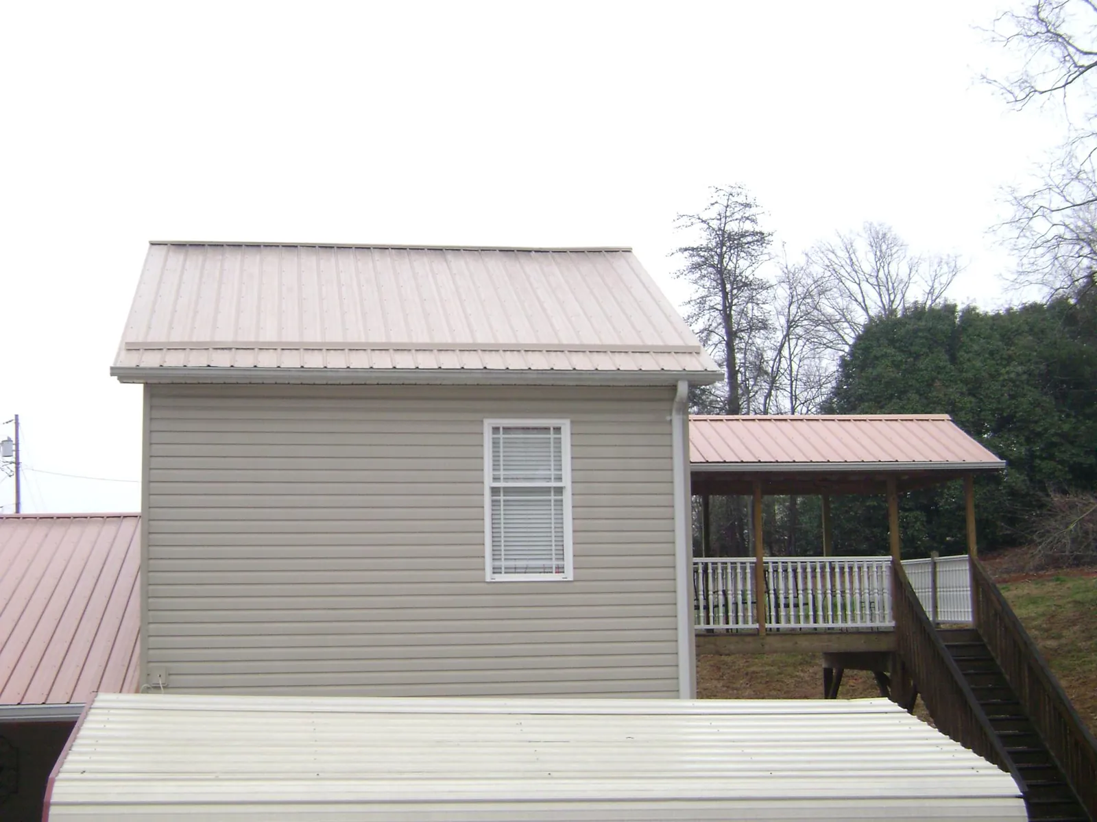 Tan metal roofs on a two story addition and attached porch, from a Roof Replacement job in Keyport
